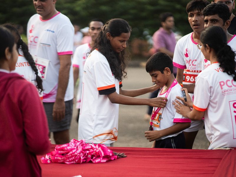 A volunteer places a finisher medal around a young runner's neck.