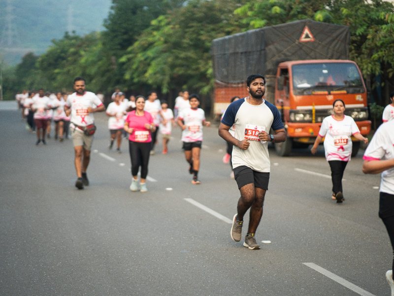 A stream of runners moves along the road through Kharghar.